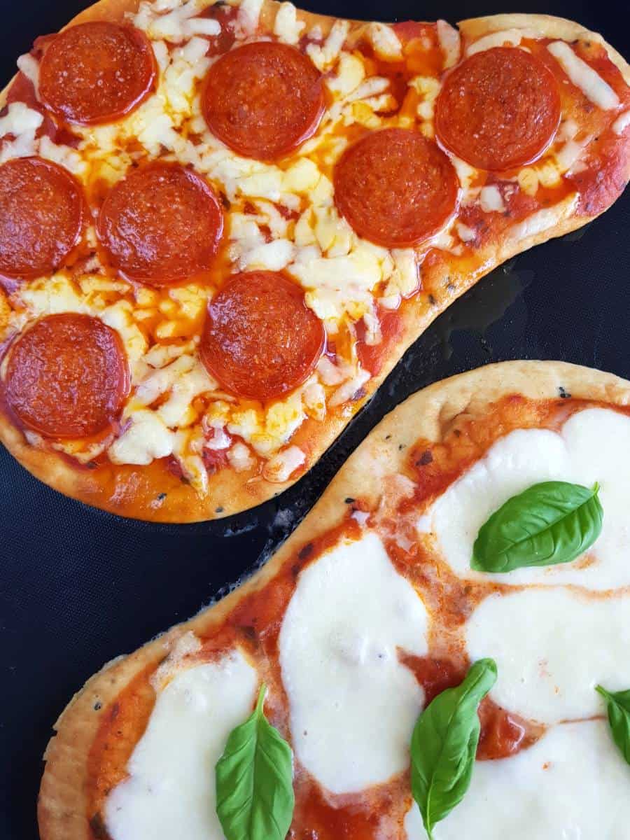 Pepperoni naan pizza on a baking sheet.